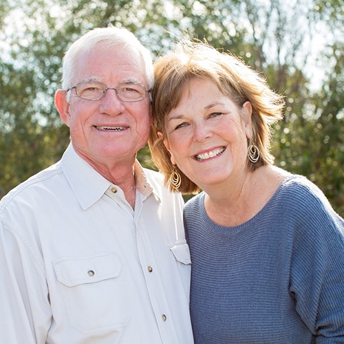 Older couple with dentures in North Naples smiling outside