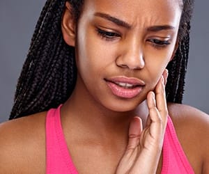 Woman with toothache holding jaw in pain