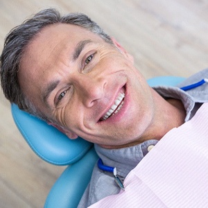 Man with greying hair smiling while laying in dental chair