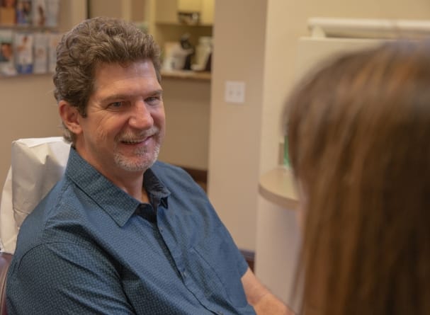 Dental patient smiling at dentistry team member during dental implant consultation