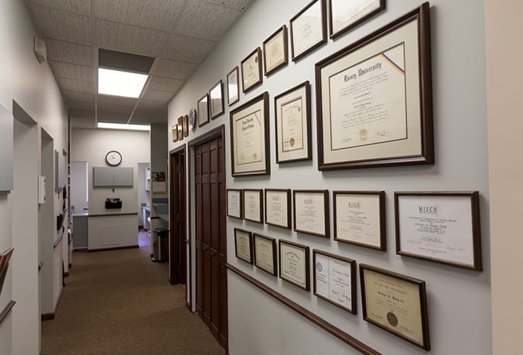 Diplomas and certifications hanging on dental office hallway wall