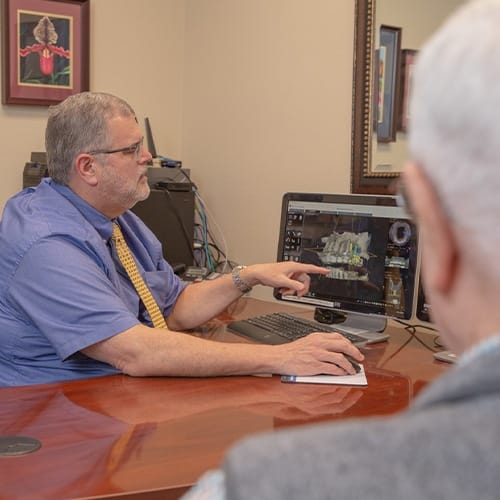 Dentist and patient reviewing ridge augmentation plan on computer screen