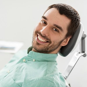 Man in green collared shirt smiling in dental chair