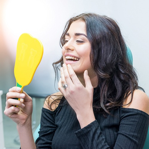 Woman looking at reflection in yellow, handheld mirror