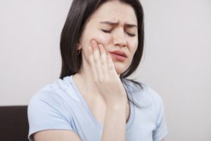 Woman with jaw pain, requires TMJ therapy from a dentist